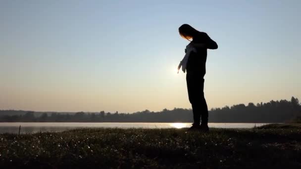 μια χαρωπή έγκυος γυναίκα παίζει με κορμάκι μωρού κατά το ηλιοβασίλεμα το φθινόπωρο - Πλάνα, βίντεο