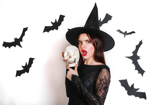 Happy gothic young woman in witch halloween costume with hat standing and having fun over white background - Foto, immagini