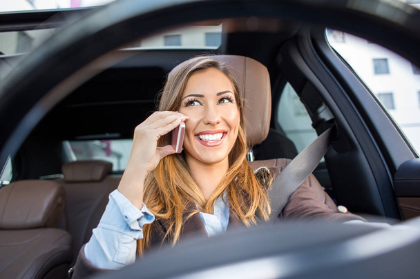Beautiful businesswoman talking on the phone in a car - Фото, изображение