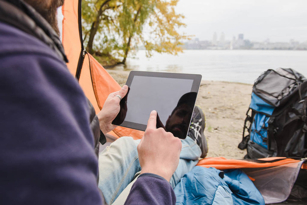 Man using digital tablet in camping tent - 写真・画像