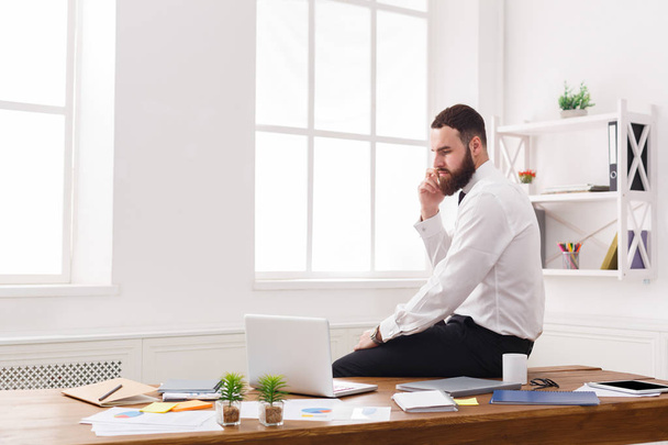 Серйозний бізнесмен у формальному одязі має розмову на мобільному телефоні в сучасному білому офісі
 - Фото, зображення