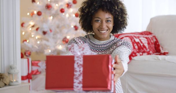 усміхнена дружня жінка, що пропонує різдвяний подарунок
 - Фото, зображення
