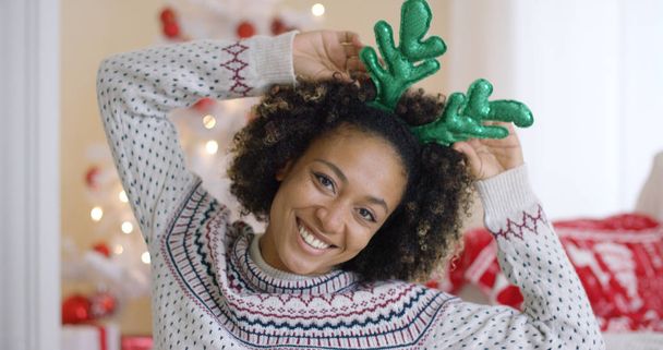 Playful young woman wearing green reindeer antlers - Photo, Image