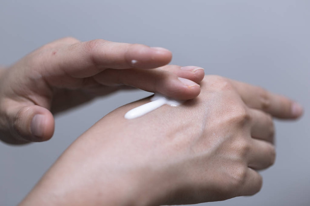 Young woman is using white lotion on her hand, beauty concept - Φωτογραφία, εικόνα
