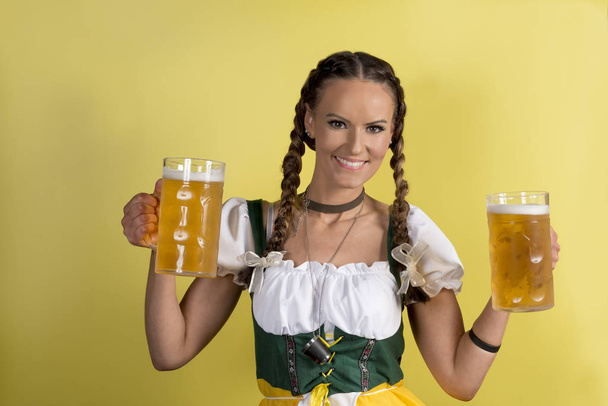 Oktoberfest κορίτσι σε παραδοσιακά γερμανικά ρούχα με κούπες με μέλισσα - Φωτογραφία, εικόνα