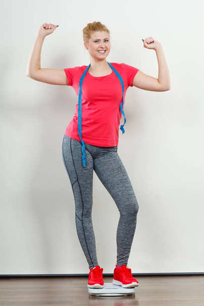 Woman wearing sportswear standing on weight machine - Fotoğraf, Görsel