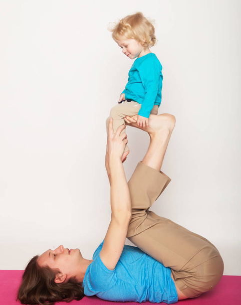 concepto de deporte y personas: padre y su hijo haciendo ejercicio de yoga en el fondo blanco del estudio
. - Foto, Imagen