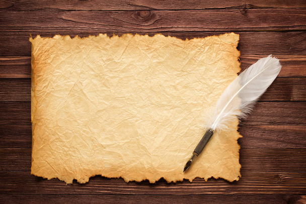 White feather and old paper on wood surface - Valokuva, kuva