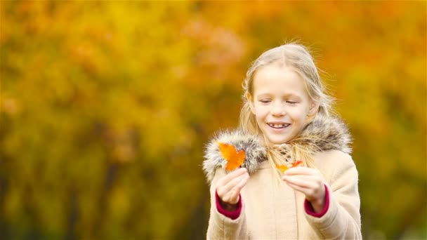 Małe dziecko na zewnątrz bawić się w piękny ciepły dzień z żółty liść jesieni - Materiał filmowy, wideo