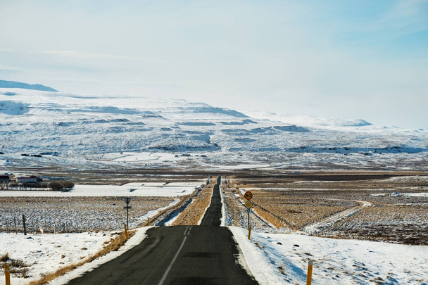 Estrada rural vazia no inverno com montanha coberta de neve, foco na montanha
 - Foto, Imagem