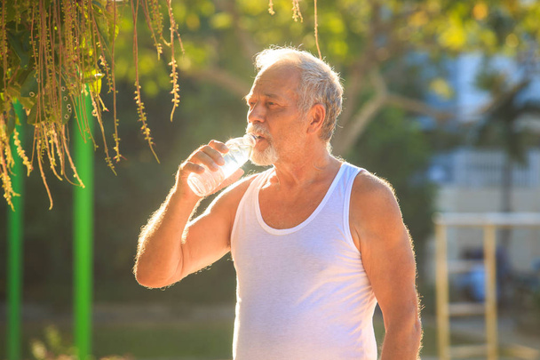 Man Holds Water Bottle in Park - Photo, image