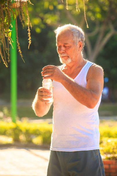 Man Holds Water Bottle in Park - Foto, imagen