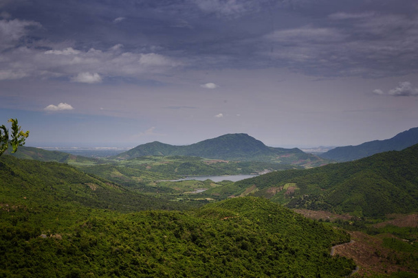 pictorial aerial view boundless green hilly valley and distant lake against blue sky with white clouds - Foto, afbeelding