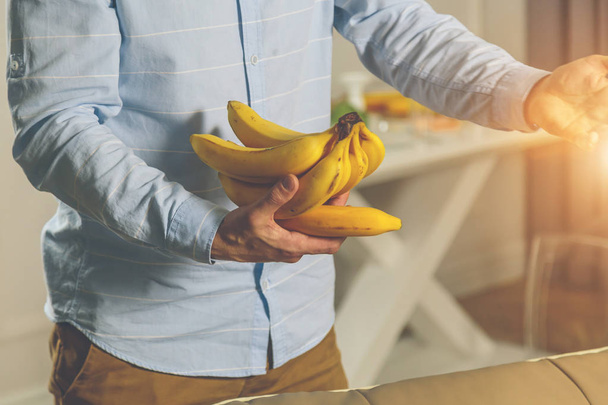 brutal man holding a bunch of bananas in his hands - Φωτογραφία, εικόνα