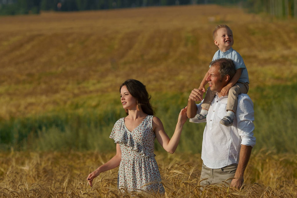 Счастливые родители и дети идут по пшеничному полю
 - Фото, изображение