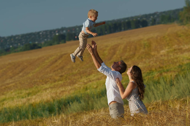 Young parents and kid walking through wheat field - Photo, Image