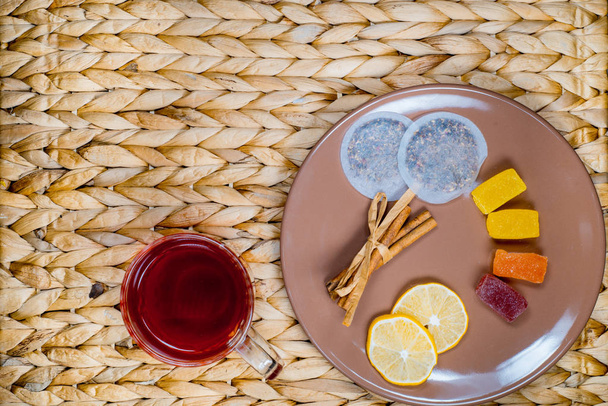 Herbal tea with cinnamon and lemon on a wicker basket. Christmas cones - Fotó, kép