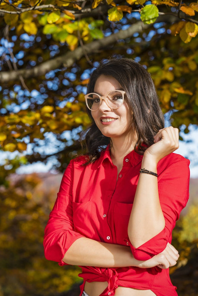 Beautiful young brunette enjoys a sunny day of autumn in nature - Photo, Image