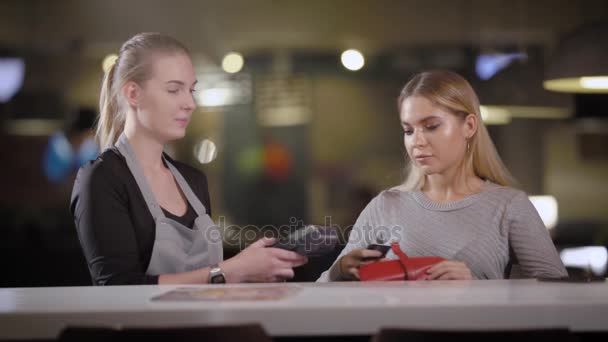 waitress is approaching to woman visitor of restaurant with payment terminal for paying the bill - Filmmaterial, Video