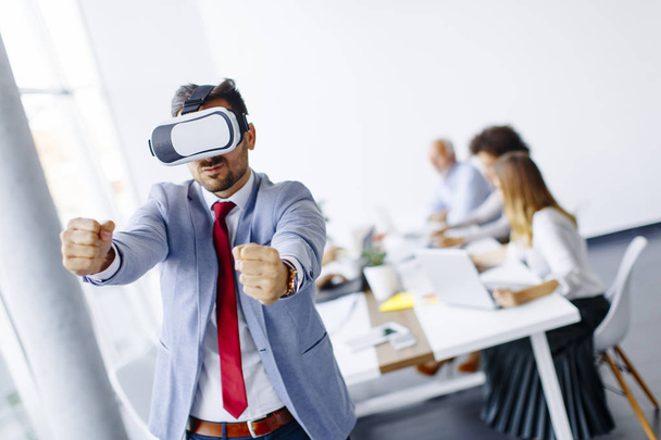 Homme d'affaires avec écouteurs de réalité virtuelle dans le bureau
 - Photo, image