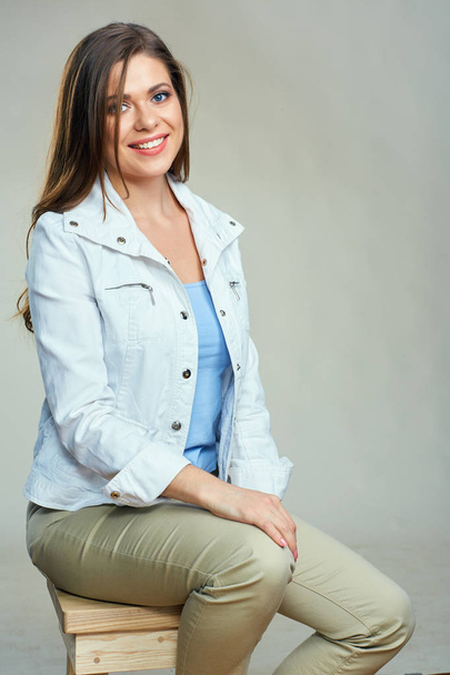 Young smiling woman wearing white jacket sitting on bar chair.  - Fotó, kép