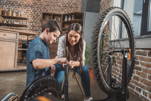 Mère et fils fixant pneu de vélo
 - Photo, image