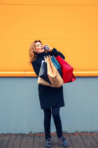 Beautiful woman with shopping bags talking on the phone. - 写真・画像