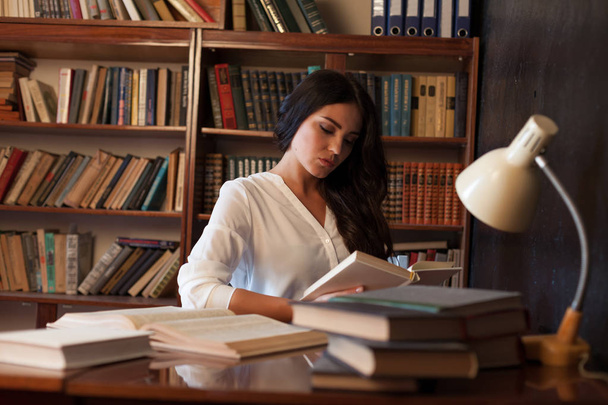 дівчина готується до іспиту читання книги в бібліотеці
 - Фото, зображення