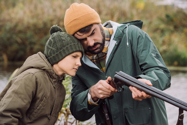 Padre mostrando hijo cómo cargar arma
 - Foto, imagen