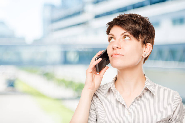 жінка з телефоном, дивлячись на білий простір в офісі
 - Фото, зображення