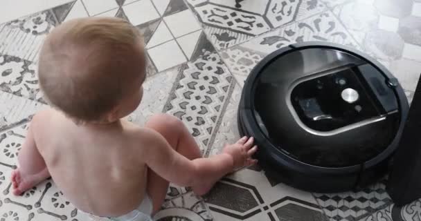 mały chłopiec i robot odkurzacz na podłodze - Materiał filmowy, wideo