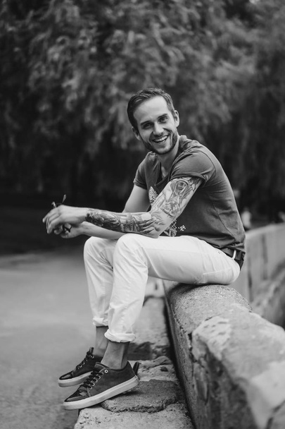 Man sitting on fence and smiling at camera - Fotografie, Obrázek