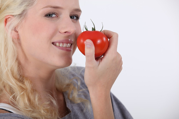 Young woman eating a tomato - Fotoğraf, Görsel