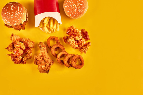 Hamburguesa vista superior, papas fritas y pollo frito sobre fondo amarillo. Copia espacio para tu texto
. - Foto, imagen