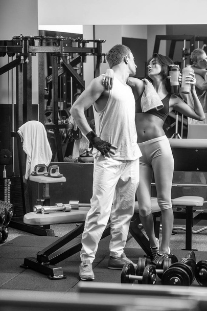muscular man and sexy girl at gym trainer with bottle - Foto, afbeelding