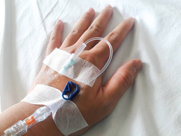 Patient hand with the tube of normal saline infusion on white cloth background - Φωτογραφία, εικόνα