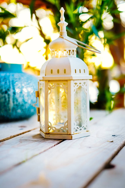 Lähikuva koriste valkoinen kynttilä lyhty puinen pöytä kaunis auringonlasku taustalla
 - Valokuva, kuva