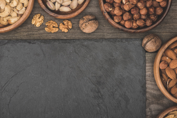 ořechy v miskách a břidlicové desky - Fotografie, Obrázek