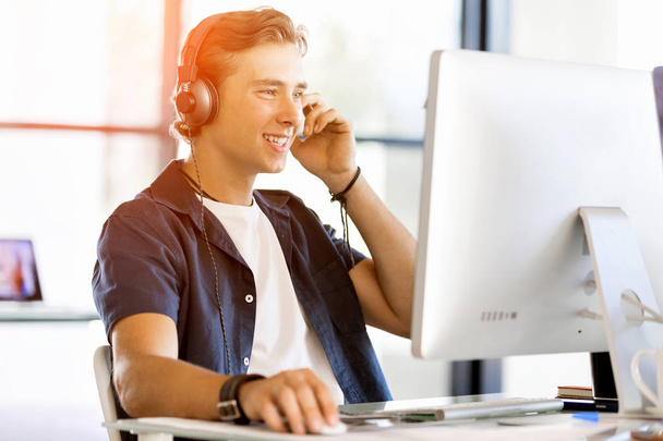 Young man in the office with headphones - Fotoğraf, Görsel