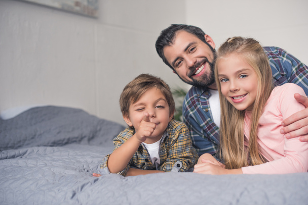 Vater und Kinder ruhen sich im Bett aus - Foto, Bild