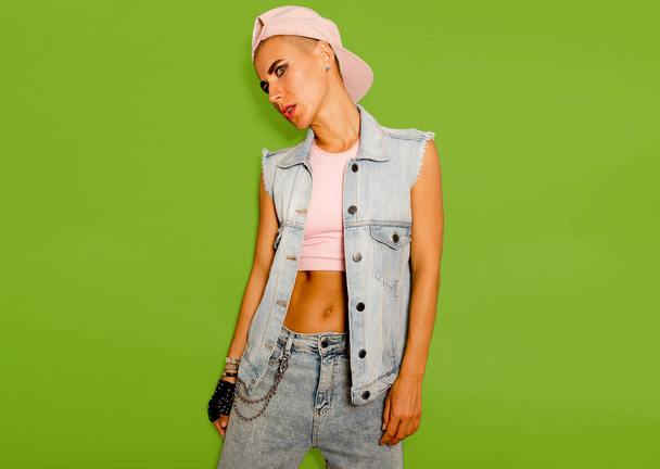 Tomboy model in denim style outfit on a green background - Foto, Bild