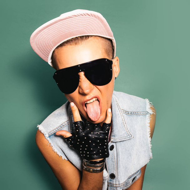  Tomboy in a stylish cap, sunglasses and glove. City jeans outfi - Foto, afbeelding
