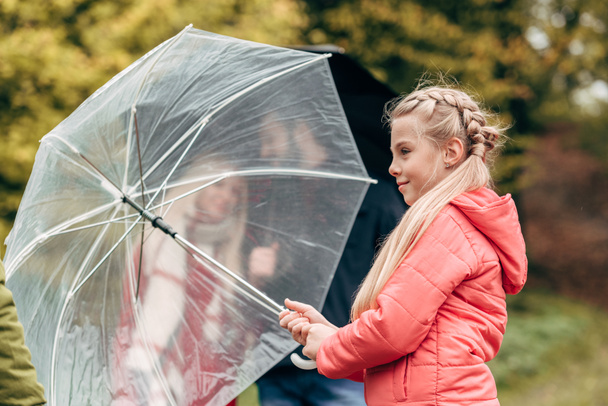 parents and daughter with umbrellas - Foto, Bild