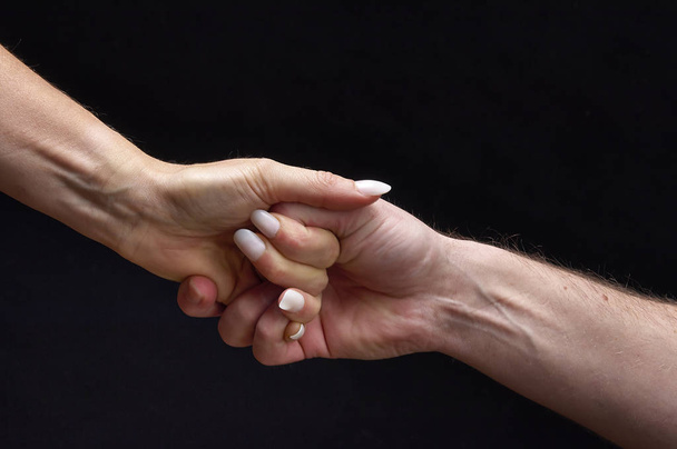 Mannelijke en vrouwelijke handen samen op zwarte achtergrond - Foto, afbeelding