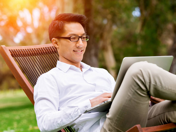 Young businessman using laptop while sitting outdoors - Foto, Imagem