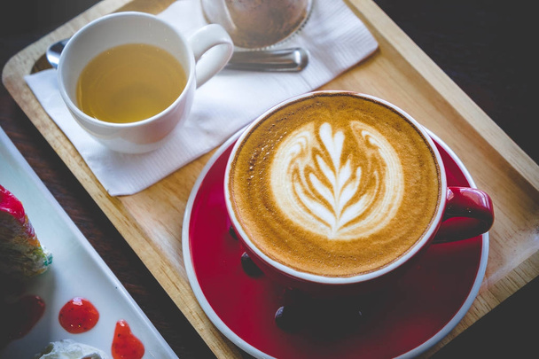 aroma caffè tazza rossa latte art e gustosa torta sul tavolo di legno in caffetteria con tono scuro vintage e spazio copia
 - Foto, immagini