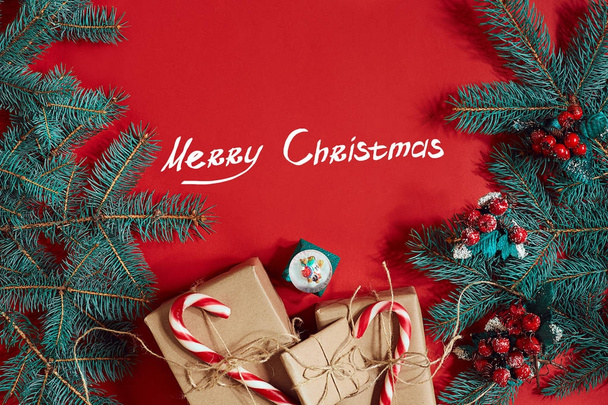 Spar tak en cadeau doos op rode achtergrond. De inscriptie - Merry Christmas - Foto, afbeelding