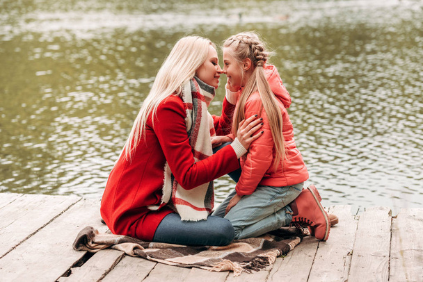 mother and daughter sitting near lake - Foto, afbeelding