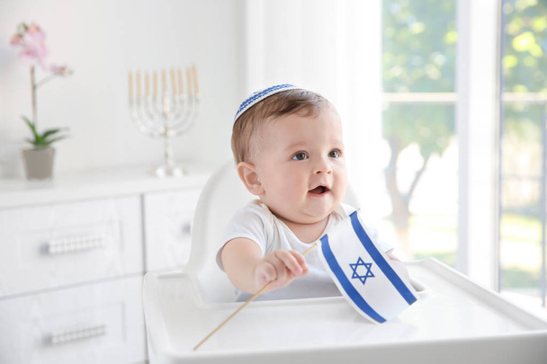 Cute baby in kippah with flag of Israel sitting on high chair at home - Photo, Image