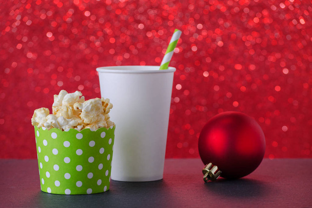 popcorn and drink in paper cup for movie and entertainment, red bokeh background, selective focus - Fotoğraf, Görsel